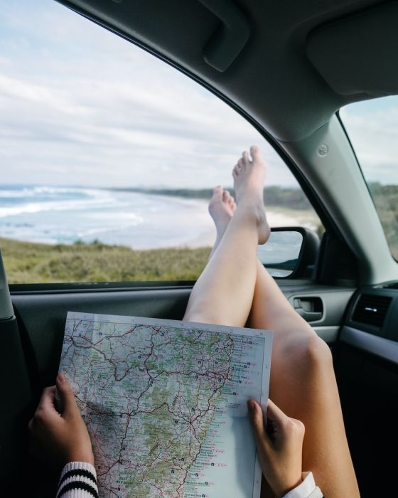 persona mirando un mapa dentro de un coche que se encuentra aparcado delante de una playa