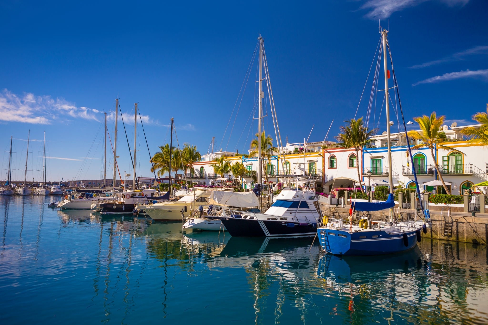 Barcos amarrados en el puerto de Mogán con casas blancas al fondo
